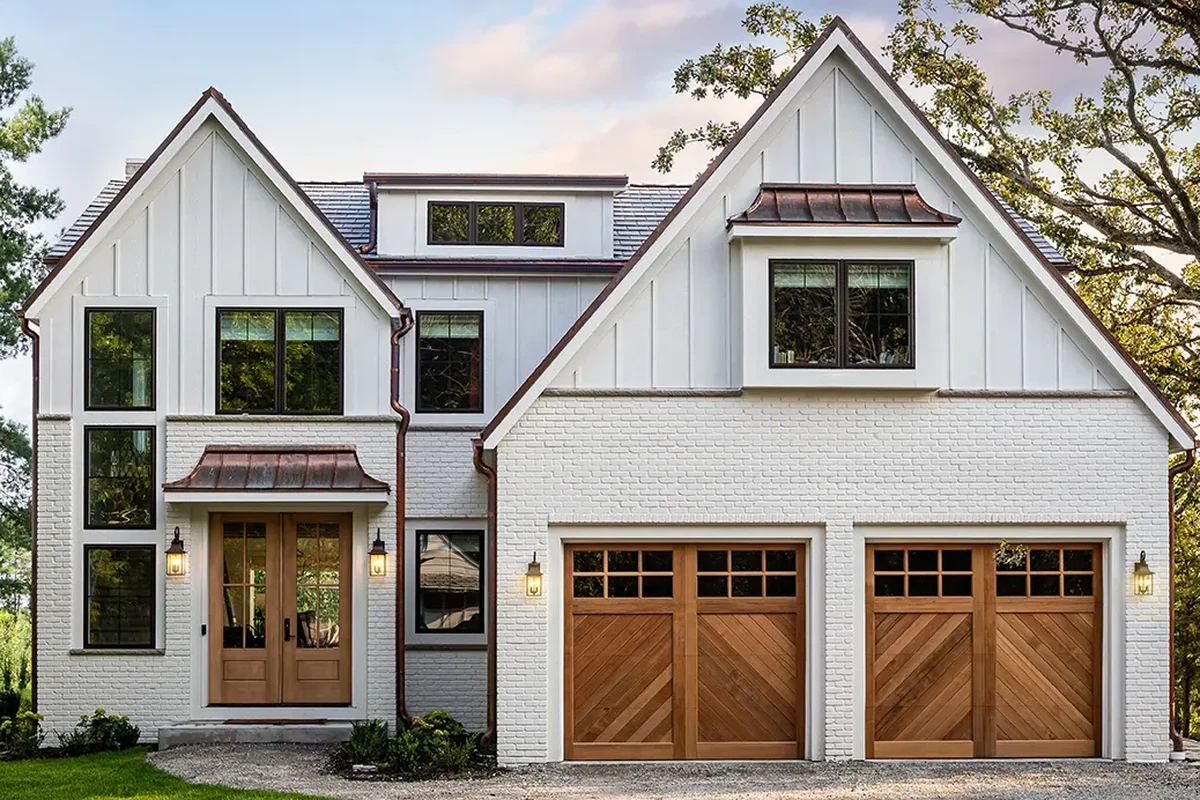 White brick home with two wood carriage-style garage doors.